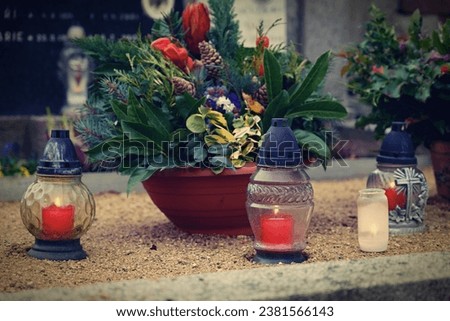 All Souls' Day. A lit candle on the grave. Background with cemetery. Autumn time and holidays. Soulstice - remembrance of the dead - Halloween holiday. 