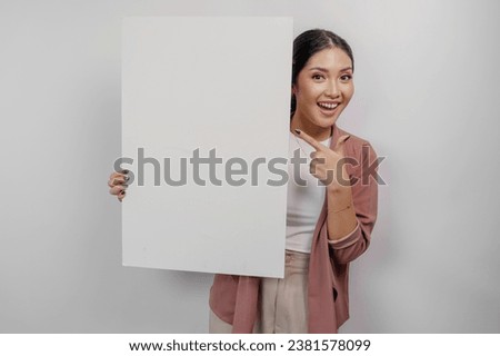 Smiling young Asian woman employee holding and showing empty blank board, isolated by white background