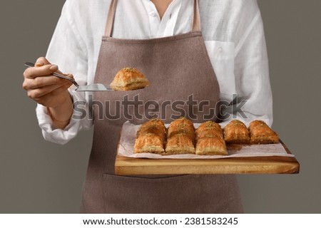 Woman with delicious sweet baklava on grey background, closeup Royalty-Free Stock Photo #2381583245