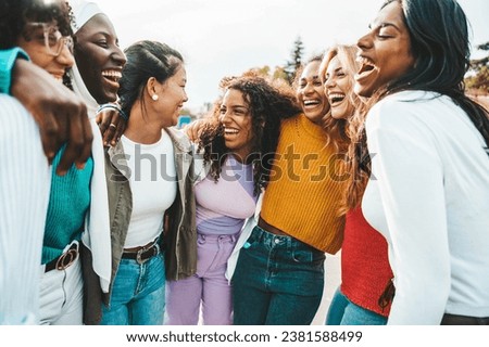 Multi ethnic group of young women hugging outside - Happy girlsfriends having fun laughing out loud on city street - Female community concept with cheerful girls standing together - Women  power  Royalty-Free Stock Photo #2381588499
