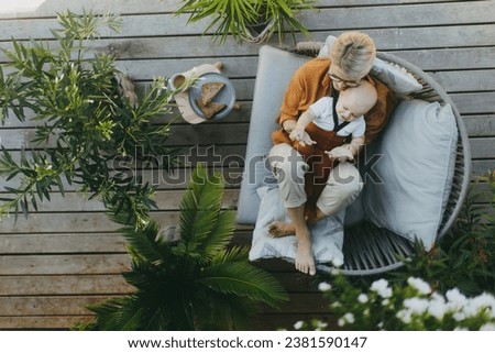 Top view of beatiful mother sitting with little son outdoors, in garden patio. Warm autumn day of mother with toddler. Hygge motherhood.