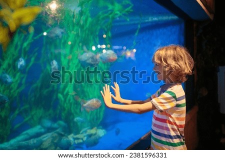 Family in aquarium. Kids watch tropical fish, marine life. Child looking at sea animals in large oceanarium. Ocean life museum. School or vacation day trip to aqua park. Royalty-Free Stock Photo #2381596331