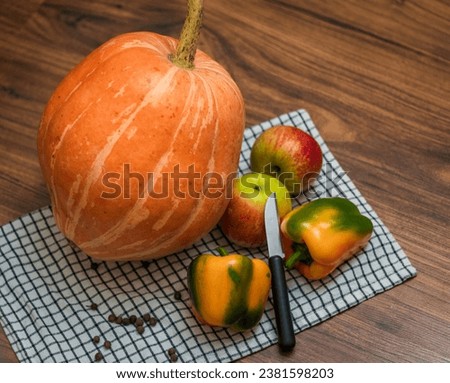 Close up shot of the pumpkin, capsicums and apples on the wooden table