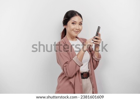 Smiling young Asian woman employee wearing cardigan while holding her phone, isolated by white background
