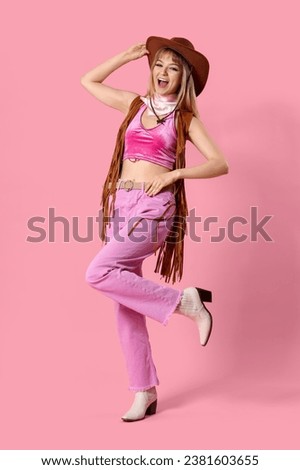 Young woman dressed as cowgirl doll on pink background Royalty-Free Stock Photo #2381603655