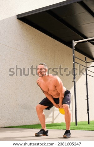 Sportsman swinging kettlebell in an outdoor training gym. Cross fit, fitness and sport.