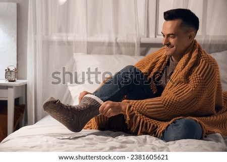 Handsome man wearing warm socks in bedroom at night Royalty-Free Stock Photo #2381605621