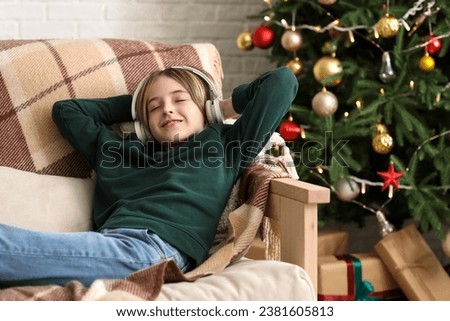 Cute little boy in headphones lying at home on Christmas eve Royalty-Free Stock Photo #2381605813