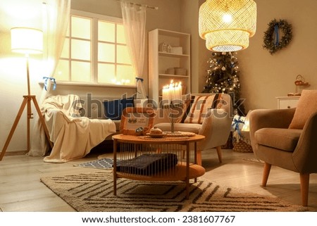 Interior of living room decorated for Hannukah with sofa, glowing lamps and table at night Royalty-Free Stock Photo #2381607767