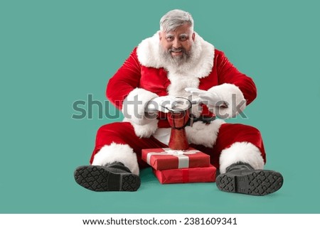 Cool Santa Claus with gift boxes playing djembe on turquoise background