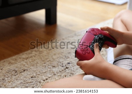 Child playing video games with controller indoors, closeup. Space for text