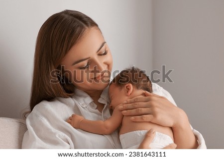 Mother holding her cute newborn baby indoors