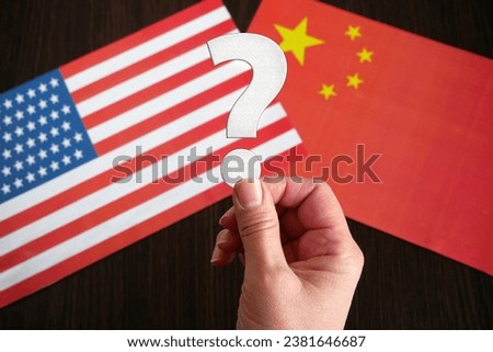 hands hold the question mark against the background of the flags of USA and China, Are countries partners or competitors? concept, closeup