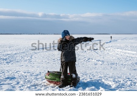 boy rides snow tubing. he points to the side with his hand. Winter joys and outdoor activities. natural light