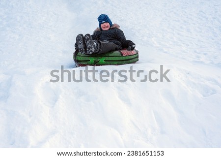 child boy riding on snow tubing downhill. Winter joy and outdoor activity. natural light