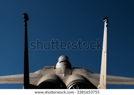 A closeup of rear of military supersonic jet F-15 eagle blue sky background Royalty-Free Stock Photo #2381653755