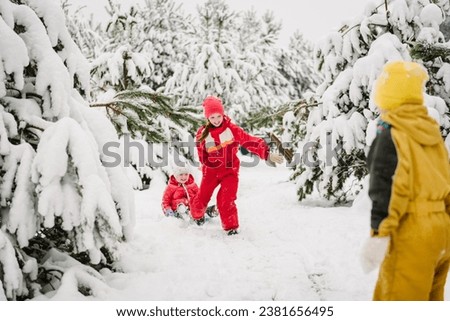 Children are rolling down hill on sledge in forest. Happy funny childs ride sled on snowy road in mountains. Family with kids walk during snowfall in the park on winter day. Girl pulling sled on snow.