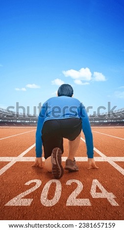 Rear view of runner man ready to run on the 2024 line. Happy New Year 2024 Royalty-Free Stock Photo #2381657159