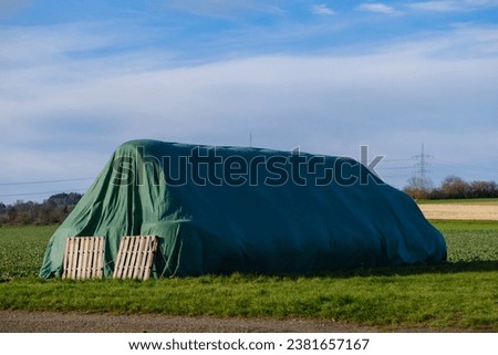 A pile of hay bales covered in a protective layer of plastic sheeting Royalty-Free Stock Photo #2381657167
