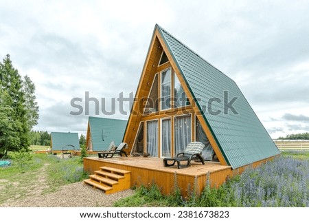 A country complex of several triangular guest houses with panoramic glazing . Country recreation in nature in an eco-hotel . Country house .  Royalty-Free Stock Photo #2381673823