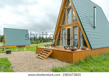 A country complex of several triangular guest houses with panoramic glazing . Country recreation in nature in an eco-hotel . Country house .  Royalty-Free Stock Photo #2381673825
