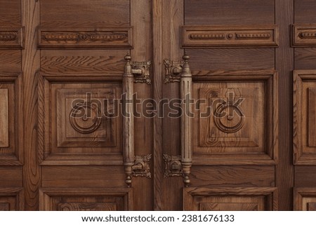 A close-up shot of an antique massive wooden door with large handles Royalty-Free Stock Photo #2381676133