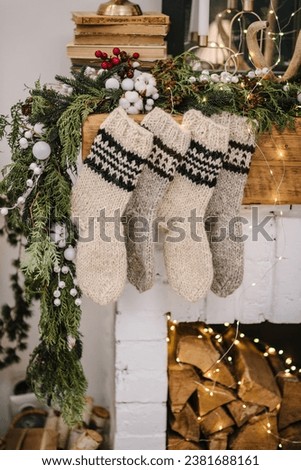 Christmas knitted woolen socks closeup. Decorative fireplace with Christmas stockings, garlands and gifts in stylish room interior. Happy New Year and Merry Christmas.