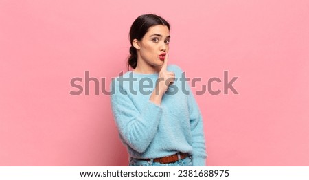 young pretty woman asking for silence and quiet, gesturing with finger in front of mouth, saying shh or keeping a secret Royalty-Free Stock Photo #2381688975