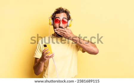 expressive crazy man covering mouth with hands with a shocked with headphones Royalty-Free Stock Photo #2381689115