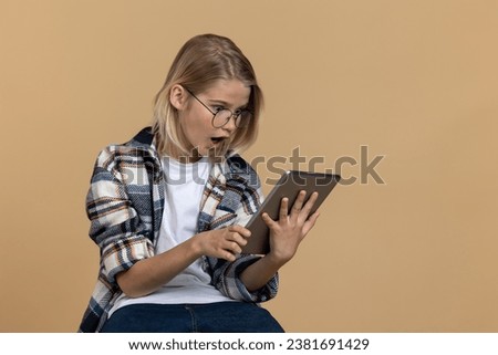 Teen girl in eyeglasses looking shocked while watching something on internet