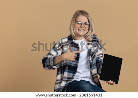 Blonde teen with a modern device looking contented