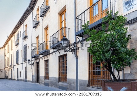 Modern narrow Spanish street in Madrid, Spain, with tiled name "Calle de la Pasa" (translation: Raisin Street), balconies, windows with bars, no people. Royalty-Free Stock Photo #2381709315