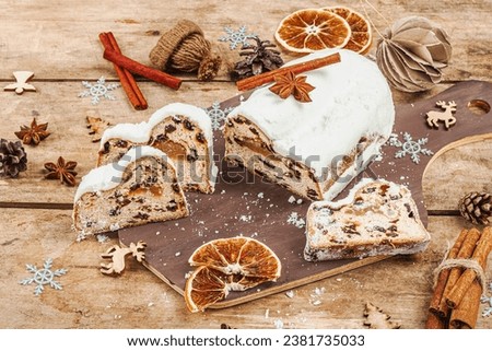 Traditional Christmas stollen, German cake. European pastry, fragrant home baked bread with spices and dried fruit. Xmas tree branches and decorations, wooden background, copy space