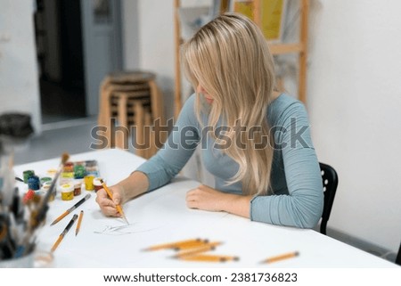 young female artist drawing cartoon on a paper with pencil