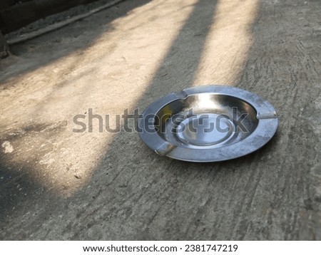 Round stainless cigarette ashtray on cement floor background