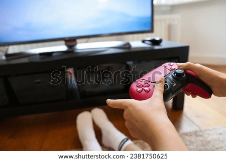 Child playing video games with controller at home, closeup
