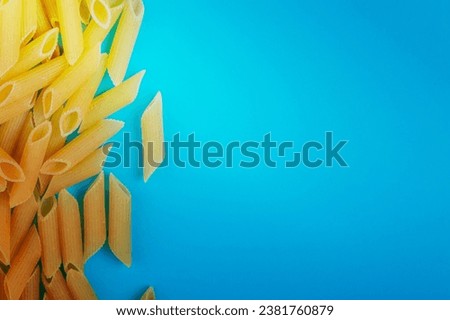 top view of penne pasta on left side and blue background with copy space Royalty-Free Stock Photo #2381760879