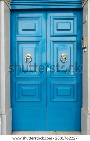 This stock photo features a stunning blue double door entrance to a brick building, adorned with elegant and decorative knockers Royalty-Free Stock Photo #2381762227