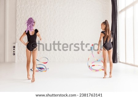 Rhythmic gymnastics. Girls gymnasts doing exercise with art ribbon on training in gym. Children's professional sports.