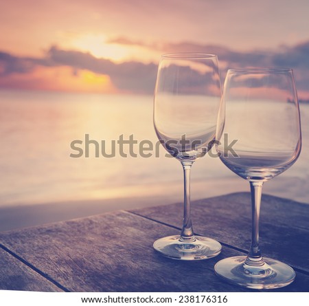 two empty glasses on a table in a cafe on the background of the setting sun