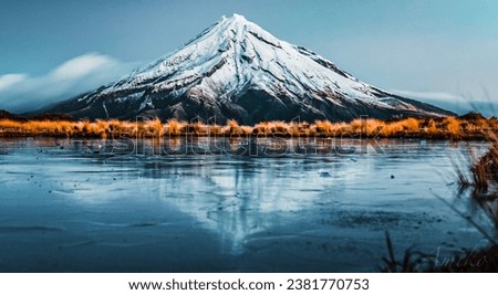 A stunning landscape of snow-capped Mount Taranaki across a tranquil lake Royalty-Free Stock Photo #2381770753