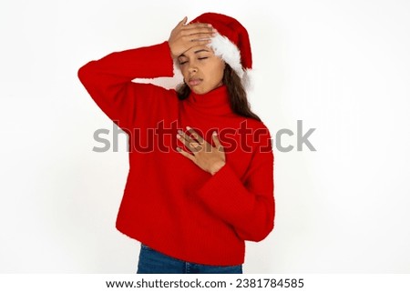 Young beautiful woman wearing red sweater and a santa claus hat at christmas Touching forehead for illness and fever, flu and cold, virus sick.