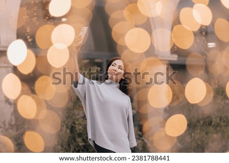 elegant woman taking a photo with her phone in a place with bright out-of-focus lights