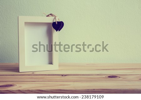 White photo frame on wooden table over grunge background, Valentine concept