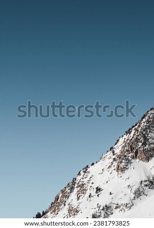 A male skier is pictured skiing down a steep, snow-covered mountain slope under a clear night sky with a bright, full moon in the background