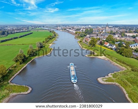 Cargo ship cruising on the river IJssel near Zutphen in the Netherlands Royalty-Free Stock Photo #2381800329