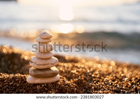 Pyramid of stones lies on small pebbles in the sun