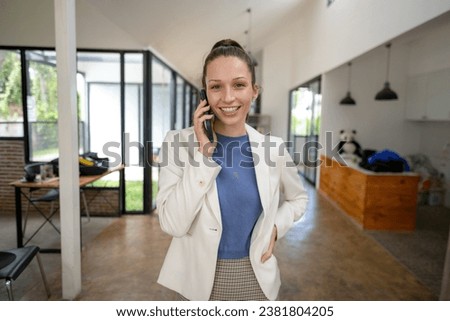Smart businesswoman stands using the phone in the office.
