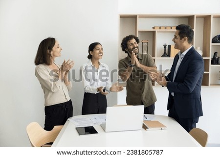 Cheerful team of diverse professionals applauding happy Indian businessman, congratulating team leader successful startup project, job success, celebrating teamwork business achievement Royalty-Free Stock Photo #2381805787