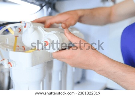 Plumber installs or change water filter. Replacement aqua filter. Repairman installing water filter cartridges in a kitchen. Installation of reverse osmosis water purification system Royalty-Free Stock Photo #2381822319